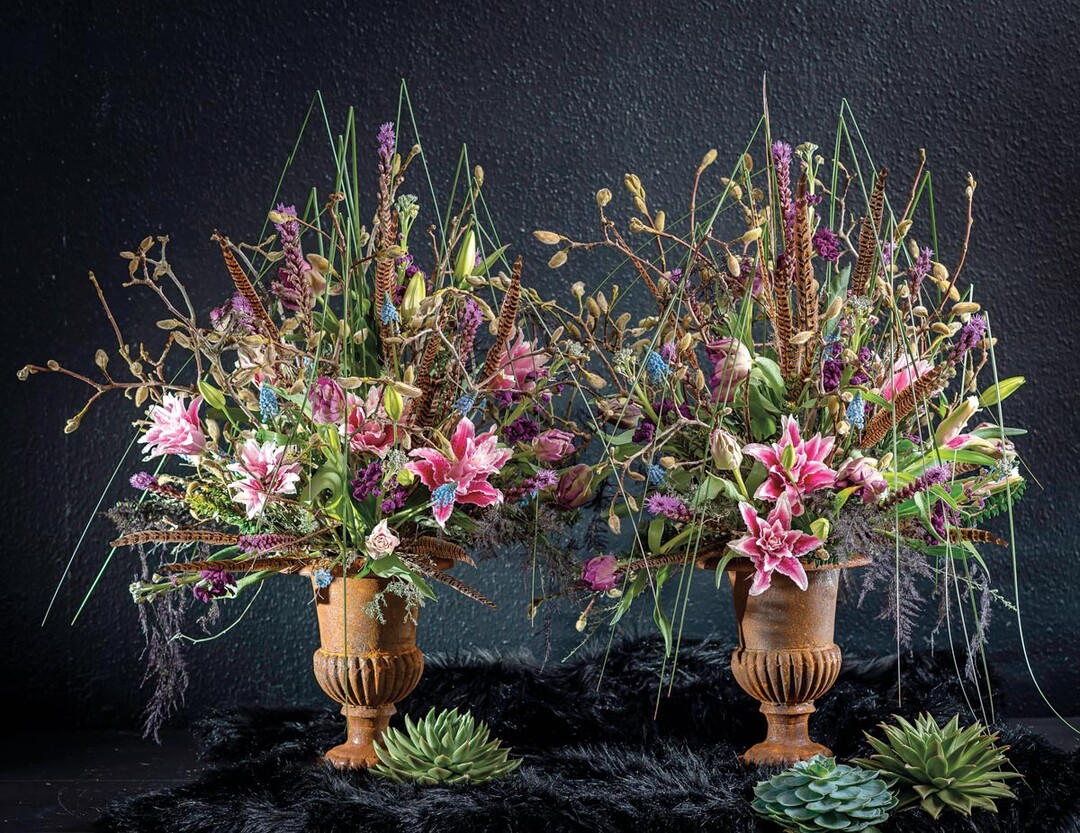 Moderne Interpretation für barocke Pokale: Wenn Christopher Ernst die Wahl hat, bleibt er seinem Stil treu. Mit diesen Gef..füllungen wollte er zeigen, wie barocke Pokale moderner und luftiger als üblich mit Blumen ergänzt werden können. Zu Magnolienzweigen und geknickten Gräsern wählte der Floristmeister gefüllte Lilien, Liatris, Tulpen und Muscari. Neben der Farbgebung ist für Christopher Ernst typisch, dass er Blumen gerne mit ungewöhnlichen Materialien kombiniert, auch aus dem Tierreich, wie hier mit Fasanenfedern.